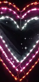 Colorful neon heart lights on dark wallpaper.