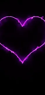 Pink neon heart glows on a black background.