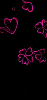 Pink neon hearts and clovers on a black background.