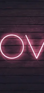 Neon pink 'Love' text on dark wood background wallpaper.