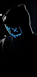 Mysterious hoodie figure with glowing neon mask in the dark.