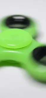 Neon green fidget spinner on a blurred background.