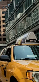 Yellow taxi driving through city street with tall buildings.