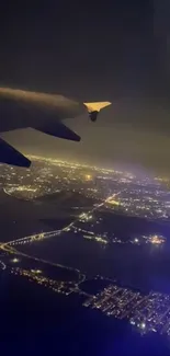 Aerial view from a plane at night highlighting city lights and dark blue sky.