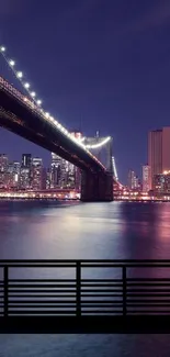 Nighttime view of a cityscape with illuminated bridge and reflections.