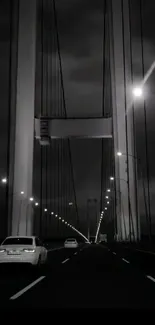 Monochrome night view of a suspension bridge with glowing lights.