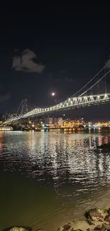 Illuminated bridge reflecting in calm night waters.