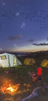 Night camping scene with tents and campfire under a starry sky.