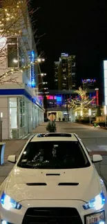 White car in vibrant night cityscape with glowing street lights.