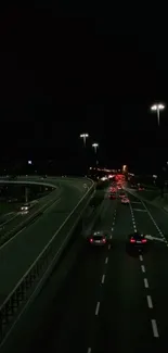 Nighttime view of cars on a city highway with illuminated streetlights.