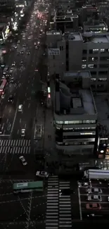 Aerial view of a busy city street at night, showcasing modern buildings and traffic lights.