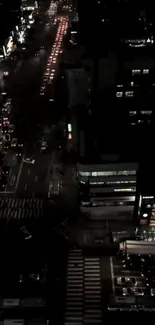 Top view of a city street at night with illuminated buildings and bustling traffic.