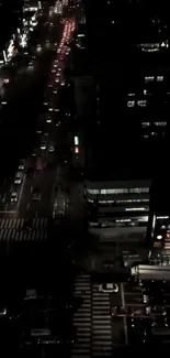 Aerial night view of city streets with traffic and illuminated buildings.