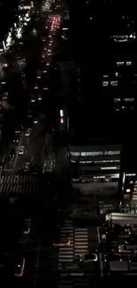 Aerial view of a busy city street at night with glowing lights and traffic.