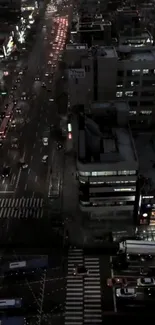 Aerial view of busy city street at night with traffic and illuminated buildings.