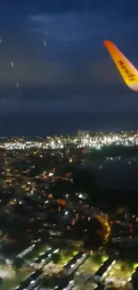 Aerial view of a city at night with airplane wing.