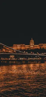 Illuminated bridge and cityscape at night with reflections on water.