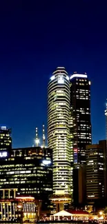 Night cityscape with illuminated skyscrapers against a dark blue sky.