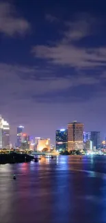 City skyline at night with reflections on water.