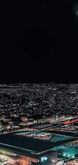 Aerial view of a city at night with vibrant lights and dark sky.