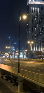 Night cityscape with illuminated high-rise buildings and empty streets.