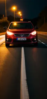 A car on a lit road at night with glowing street lights.