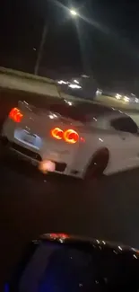 Sleek white sports car driving at night on a dimly lit highway.