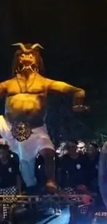 Demon statue at a night festival with crowd.