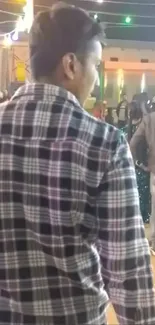 Man in checkered shirt at night festival gathering.