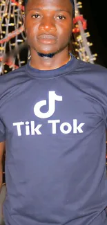 Person wearing a TikTok-themed black t-shirt at night.