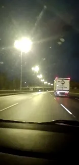 Nighttime highway with glowing streetlights and a distant moving truck.