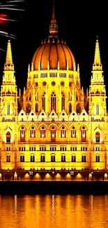 Illuminated landmark with fireworks in the night sky, reflecting in water.