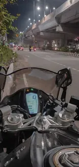 Motorcycle on city road at night under urban lights.