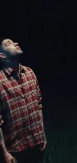 Man in checkered shirt gazing up at the night sky.