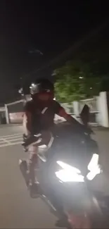 Motorcyclist riding at night with headlights glowing.