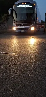 A bus traveling on a road at night, illuminated by streetlights.