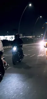 Three motorcycles cruising on a city road at night.