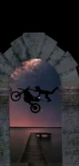 Motorbike stunt against a starry night sky through a stone arch.