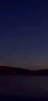 Night sky with horizon silhouettes and calm lake reflection.