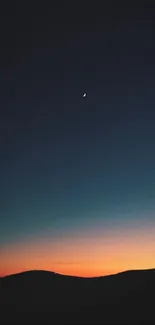 A crescent moon in a dark blue night sky over a scenic horizon.