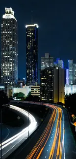 Nighttime cityscape with light trails on highway.