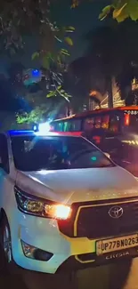 White car on a city street at night with vibrant lights.