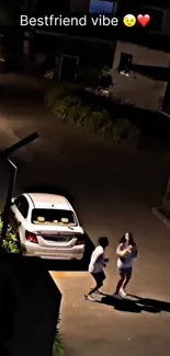 Two friends walk on a dark street near a parked car, capturing a nighttime vibe.