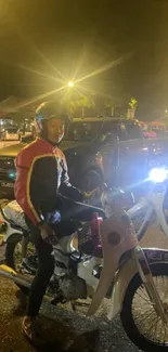 Motorcyclist riding through lively city street at night, illuminated by bright lights.