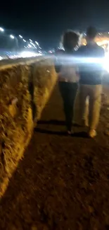 Couple walking along a stone path at night, under city lights.