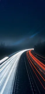 Highway at night with red and white light trails under a clear blue sky.