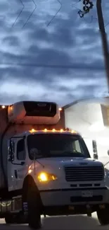 Nighttime truck driving through a cloudy sky, illuminated by streetlights.