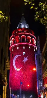 Galata Tower in Istanbul illuminated at night with vibrant red lights.