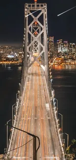 A bridge lit at night with city lights in the background, over calm water.