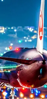 Airplane on runway at night with city in background.